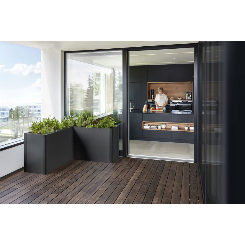 Zwei schwarze Pflanzkästen auf einem Balkon