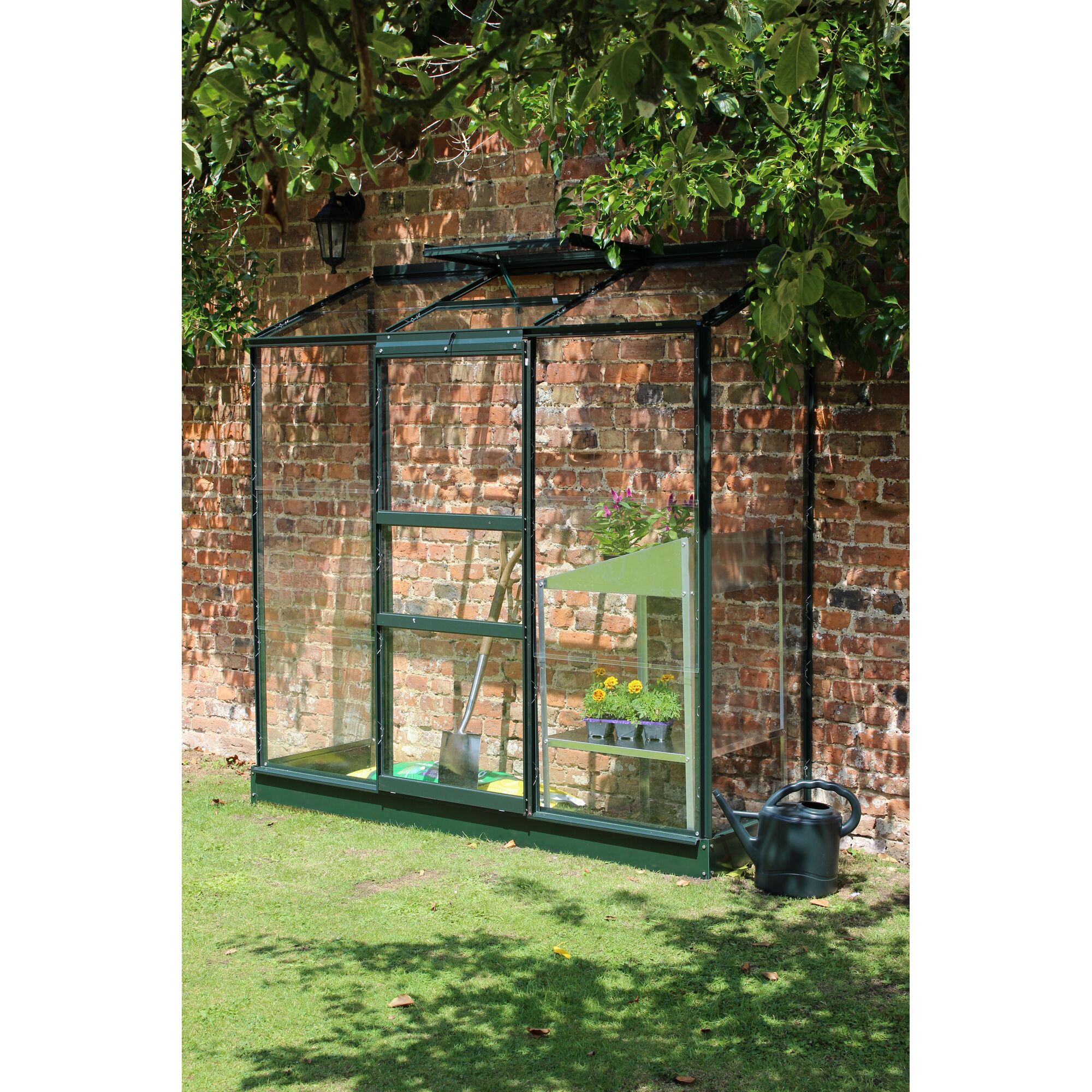 Kleines Gewächshaus an einer Backsteinmauer