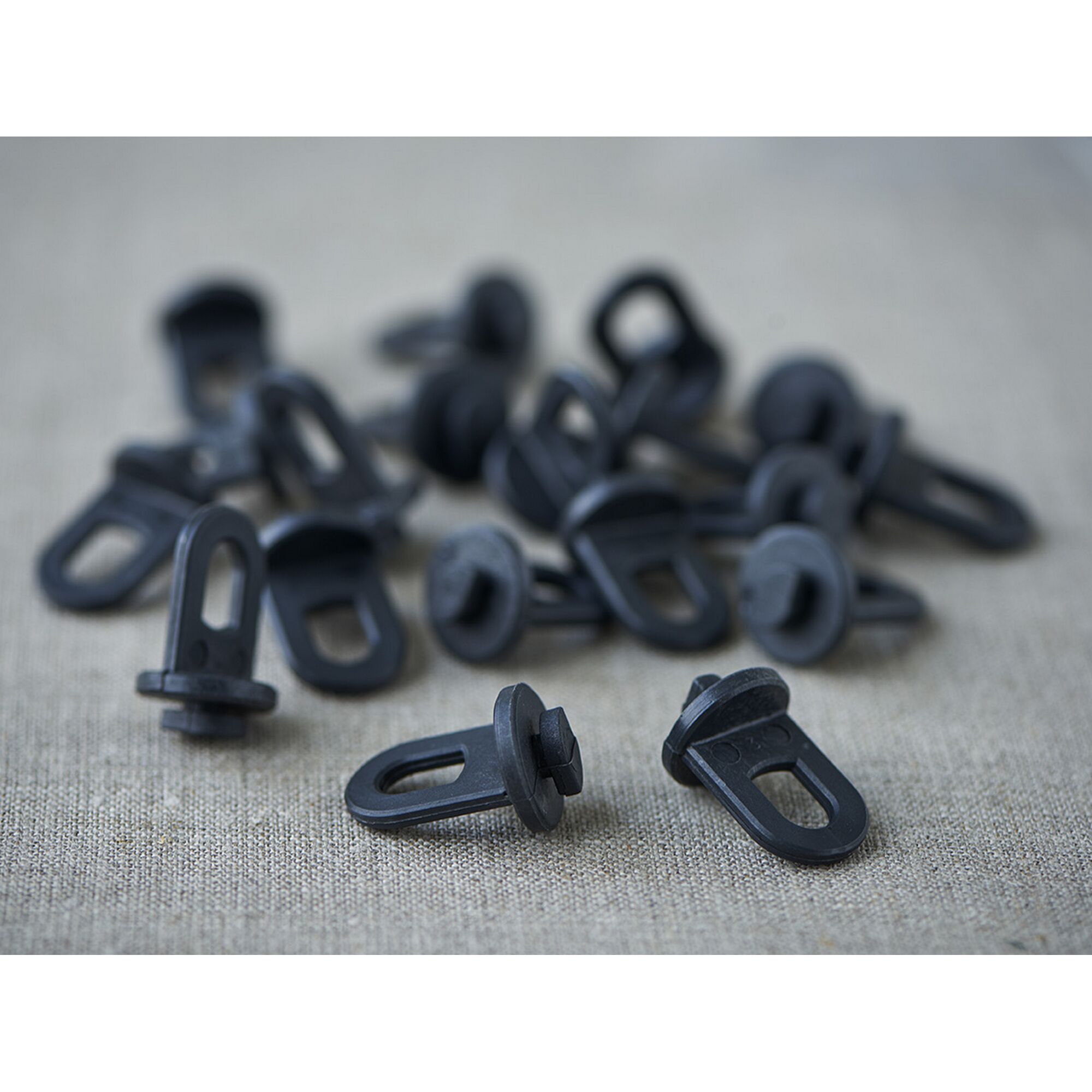 Schwarze Kunststoffösen auf grauem Stoff