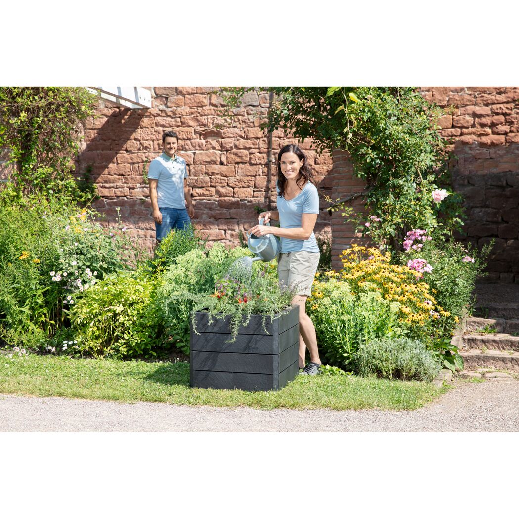 Person gießt Blumen im ERGO QUADRO S 50 Hochbeet