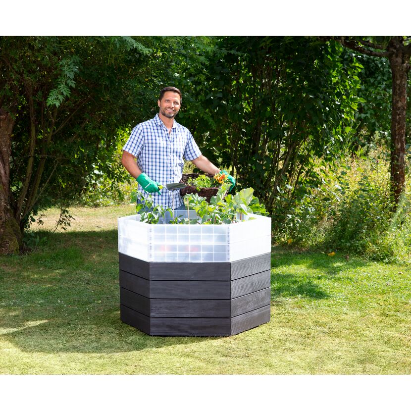 Person mit Hochbeet und Gartenhandschaufel im Garten