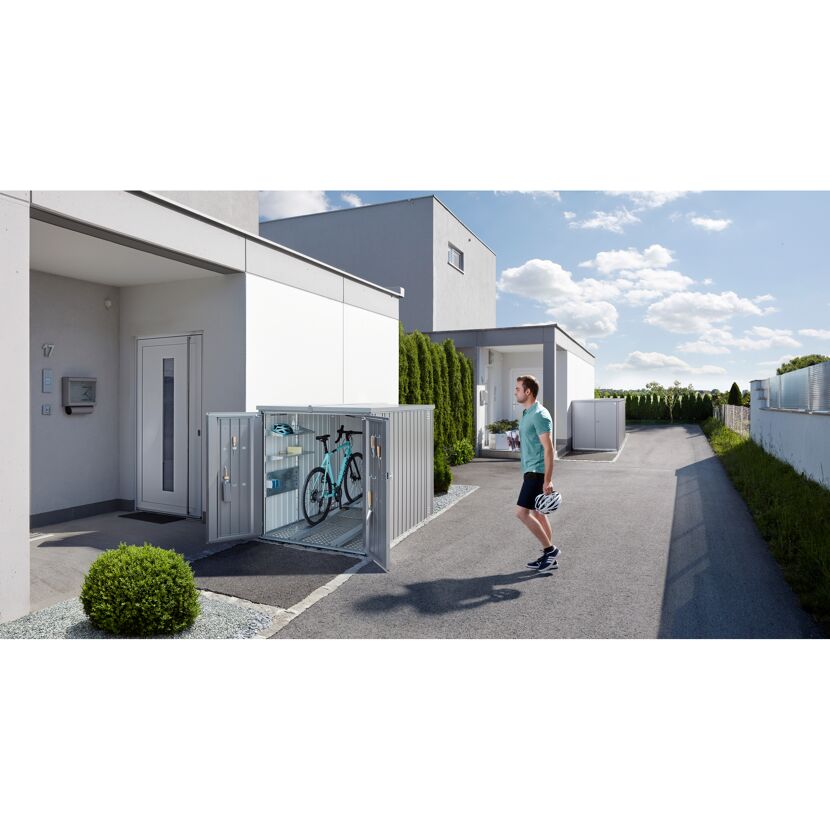 Person stellt Fahrrad in Mini-Garage silber