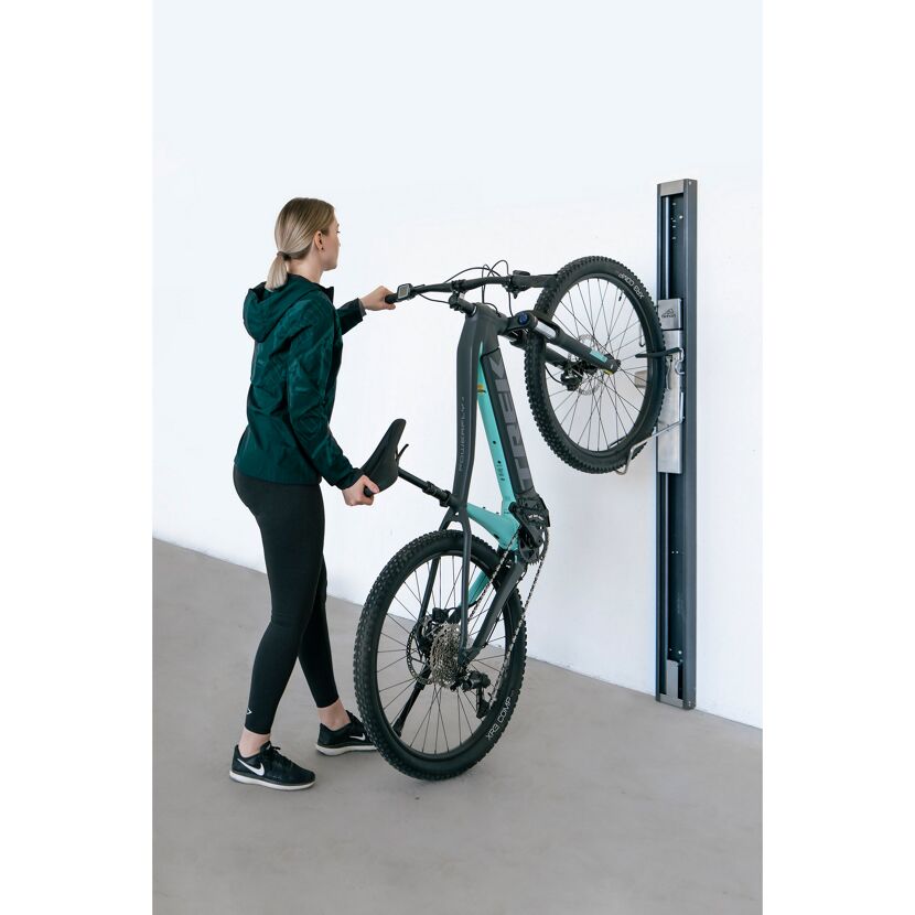 Person hängt Fahrrad an Bikelift Wandhalterung.
