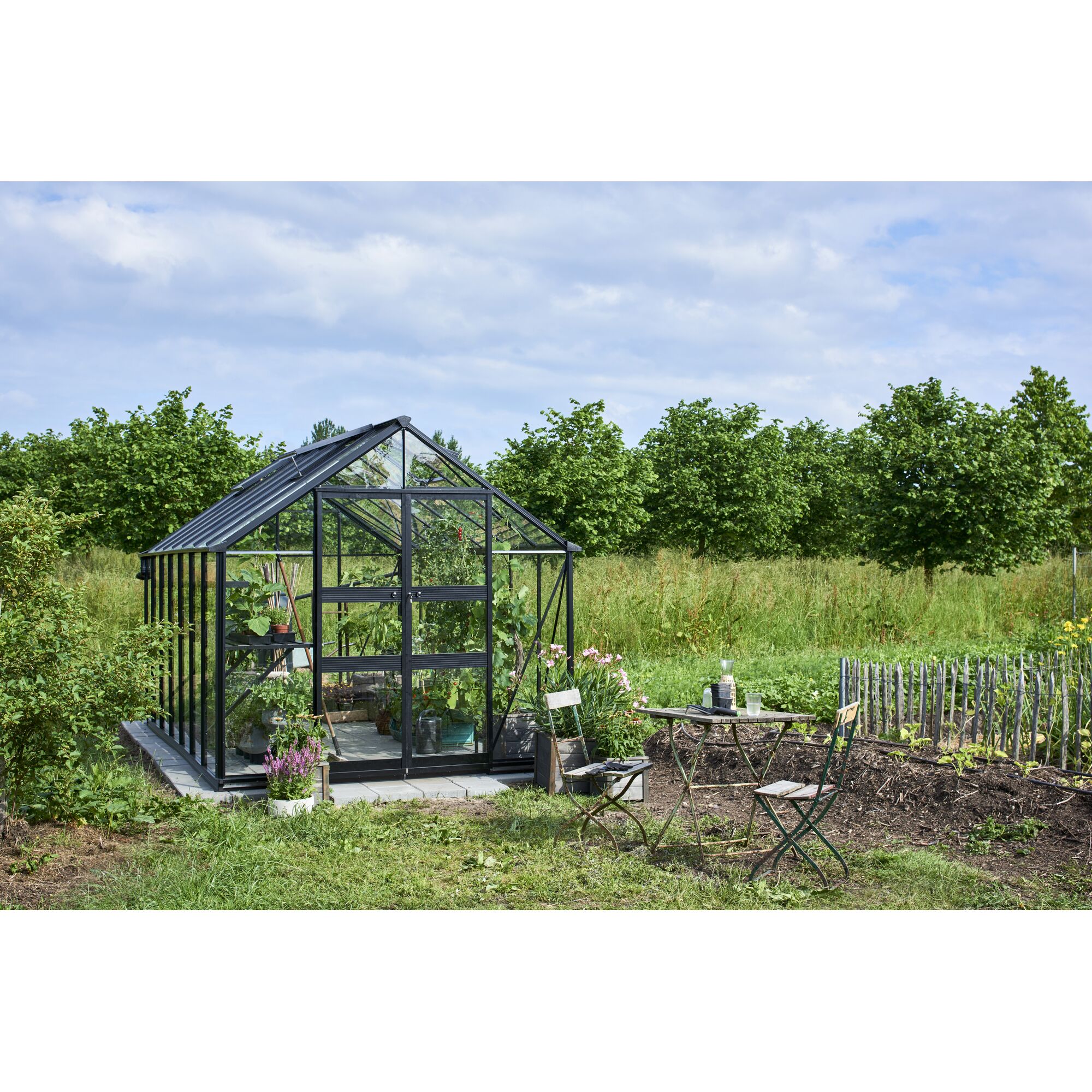 Gewächshaus Blockley im Garten mit Tisch und Stühlen