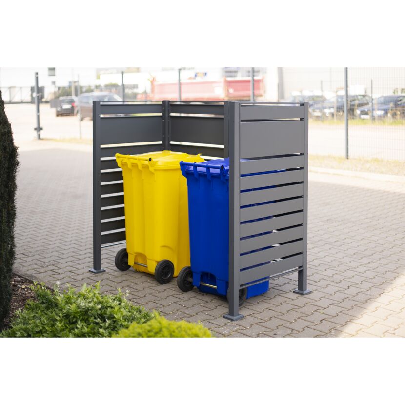 Gelbe und blaue Mülltonne in grauer Mülltonnenverkleidung