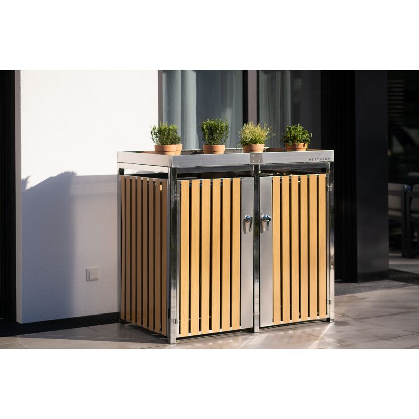 Mülltonnenbox mit zwei Türen und Kräutern darauf.