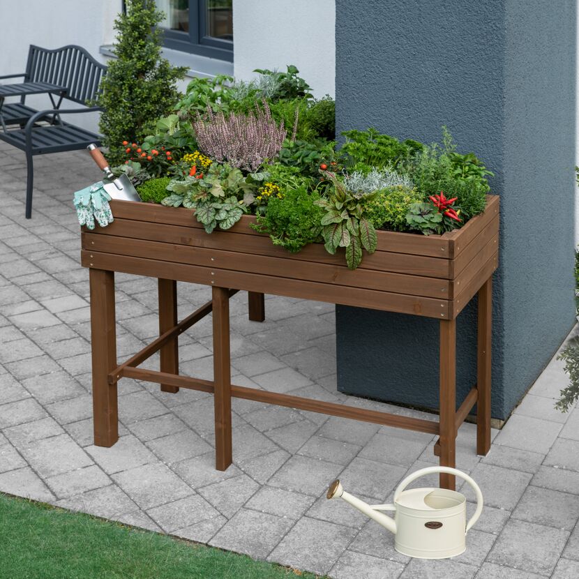 Hochbeet aus Holz mit Kräutern und Handschaufel