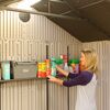 Person räumt Gartenartikel in einen Gartenschrank