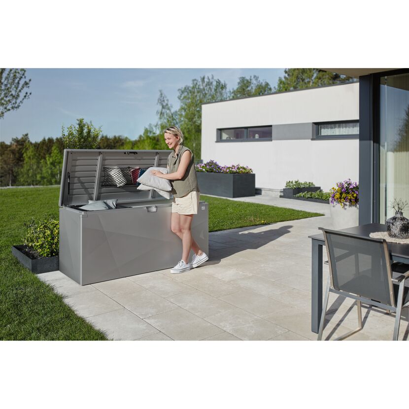 Person legt Kissen in graue Gartenbox