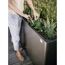 Person schneidet Pflanzen in Hochbeet mit Gartenschere