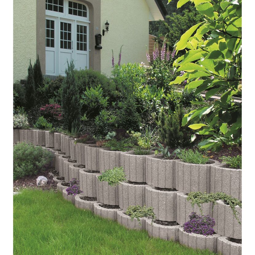 Eine erhöhte Gartenmauer aus grauen Pflanzringen.