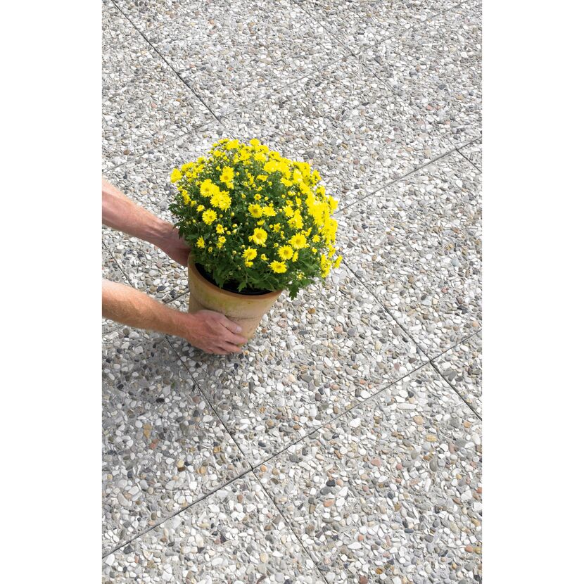 Person platziert gelbe Chrysanthemen auf Waschbetonplatten.