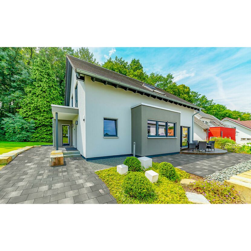 Modernes Haus mit grauem Pflaster und Garten