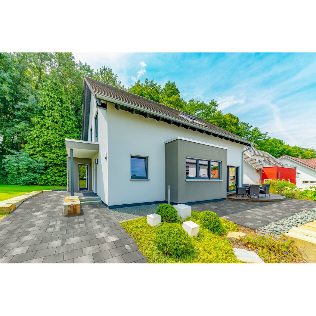 Modernes Haus mit grauem Pflaster und Garten