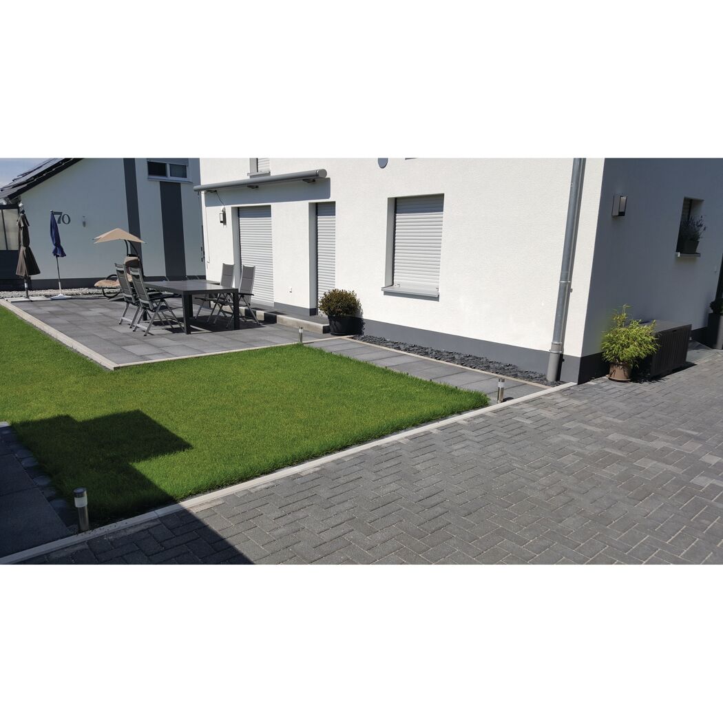 Gepflasterte Terrasse mit Gartenmöbeln und Rasenfläche