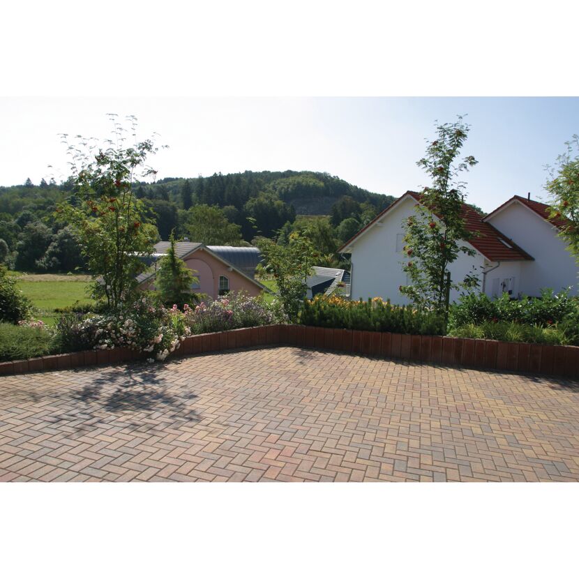 Gepflasterter Hof mit Blumenbeet und Häusern im Hintergrund