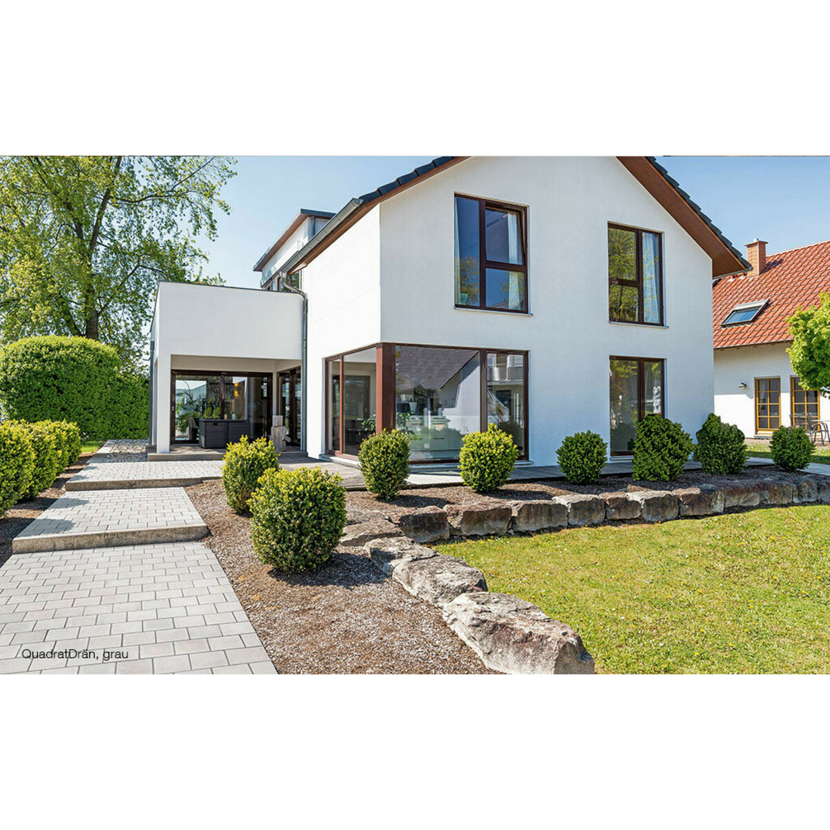 Weißes Haus mit grauem Weg und Büschen