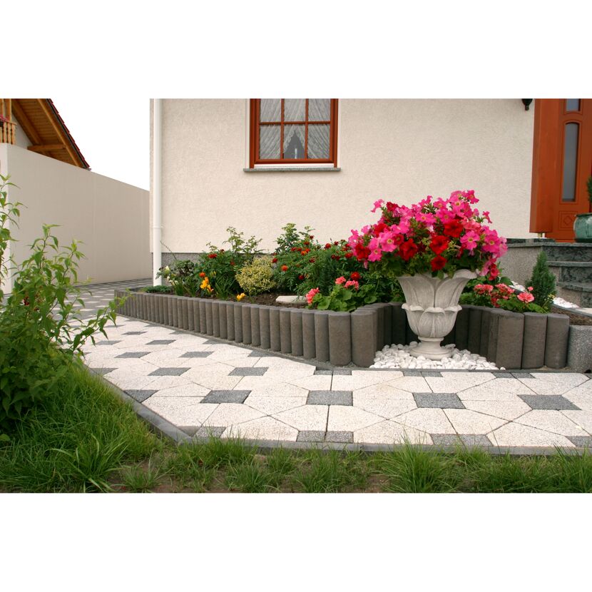 Gepflasterter Gartenweg mit Blumen und Beet