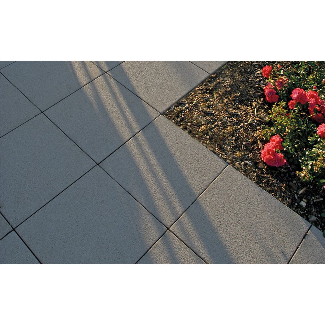 Graue Gehwegplatten neben einem Beet mit roten Blumen