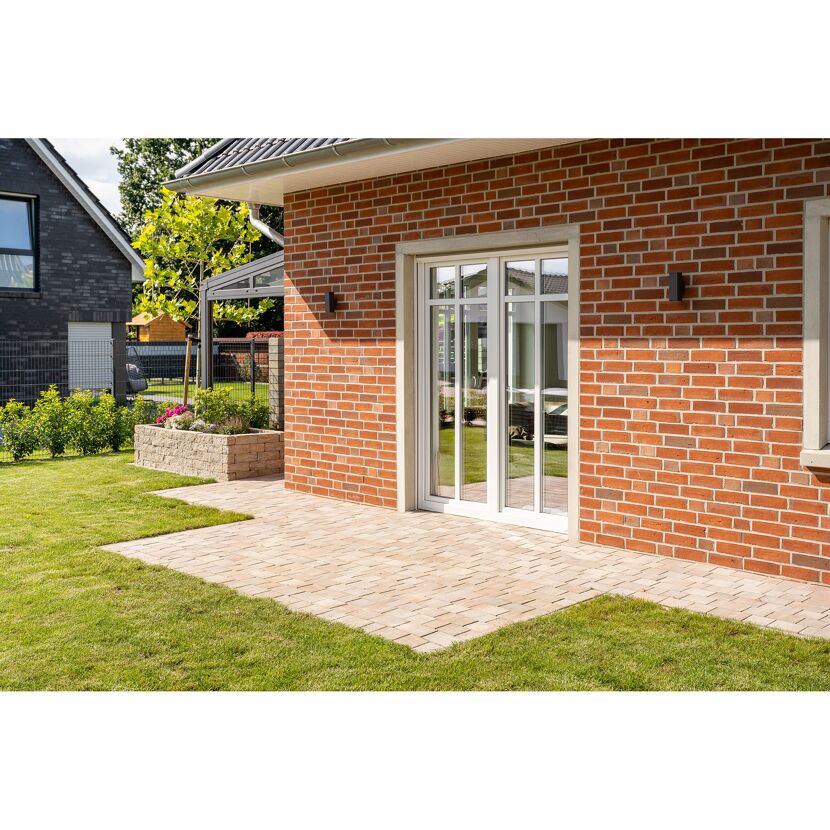 Gepflasterte Terrasse an einem Haus mit roter Backsteinmauer