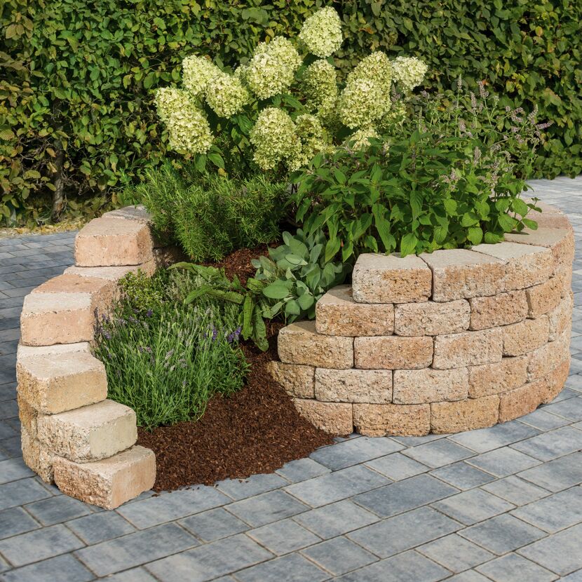 Mauerstein 'T-Wall Rustic' als Hochbeet mit Pflanzen und Blumen.