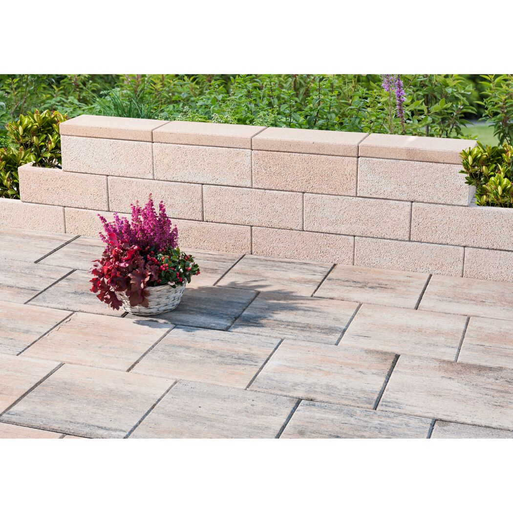 Blumenkübel auf gepflasterter Terrasse mit niedriger Mauer