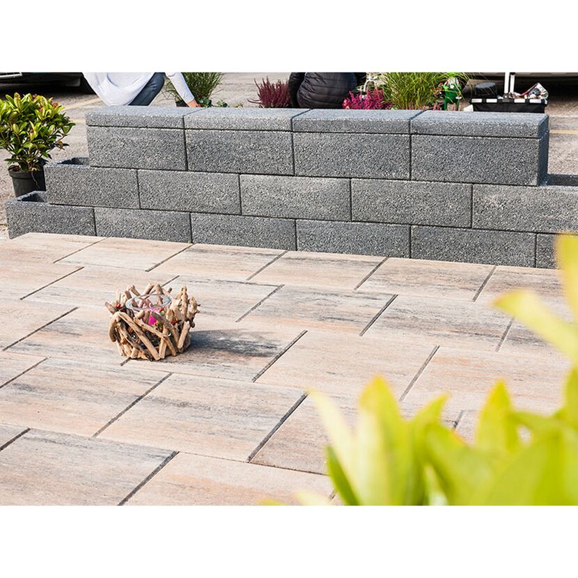 Graue Gartenmauer und beigefarbener Terrassenboden