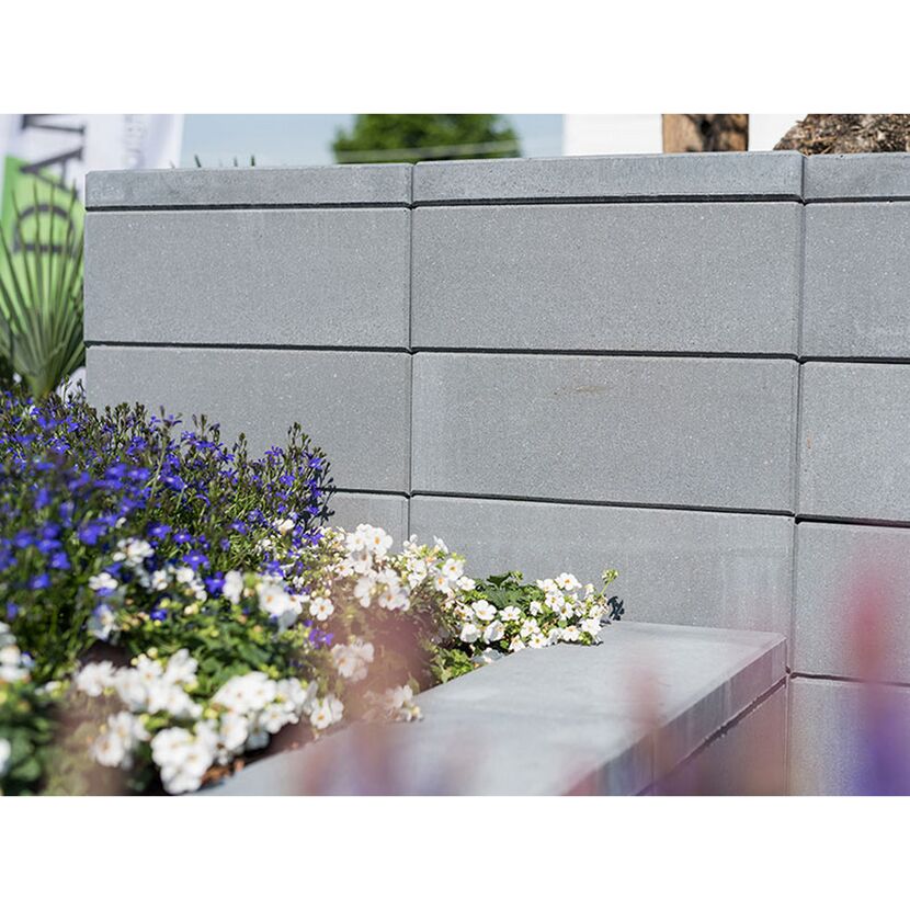 Graue Gartenmauer mit Blumenbeet