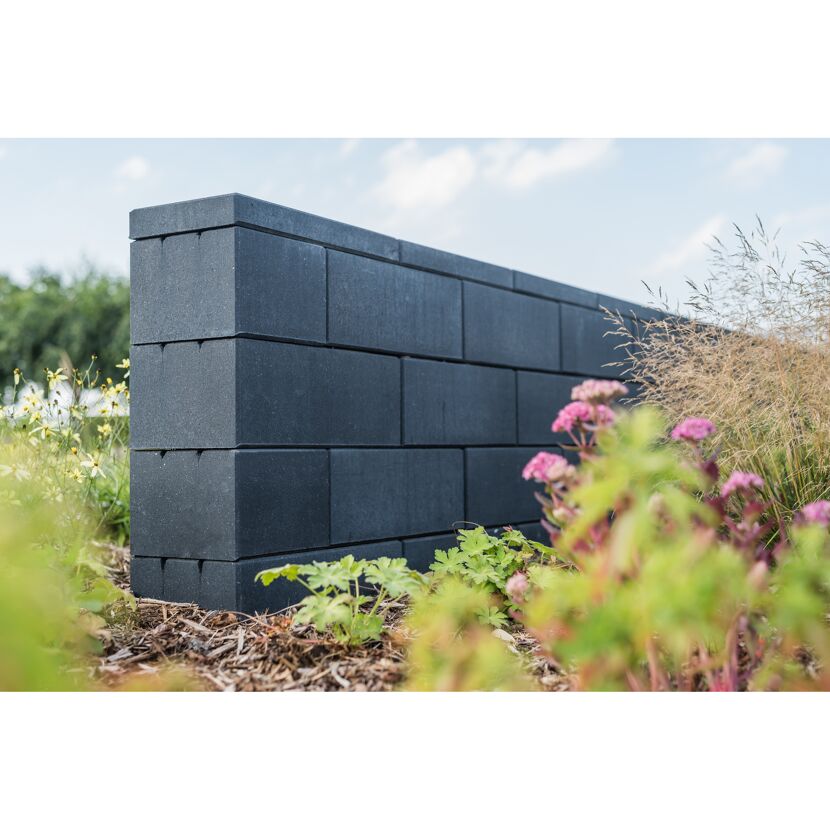 Schwarze Gartenmauer aus gestapelten Steinen