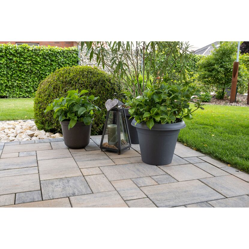 Gepflasterte Terrasse mit Topfpflanzen und Laterne