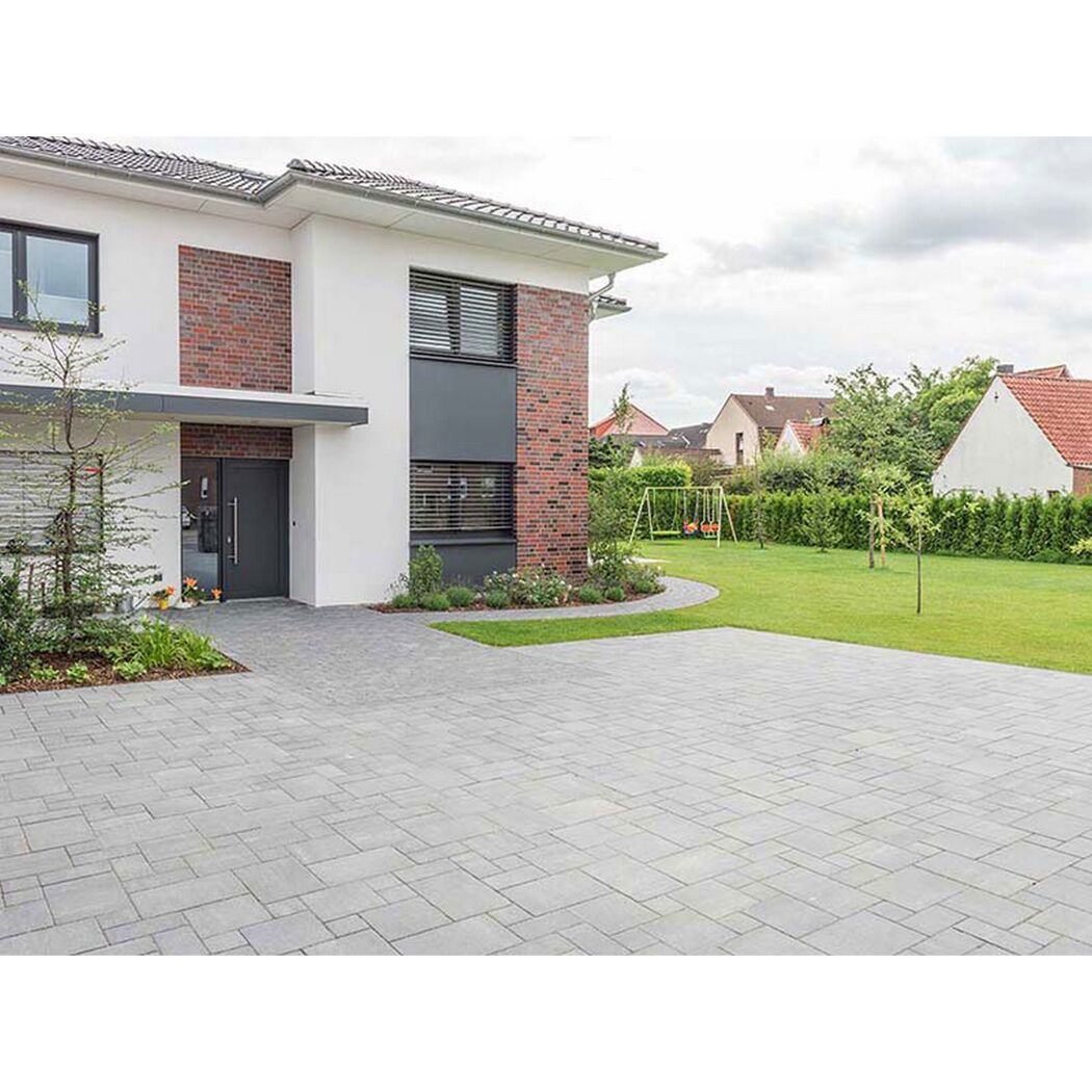 Gepflasterte Auffahrt und Vorgarten eines modernen Hauses.