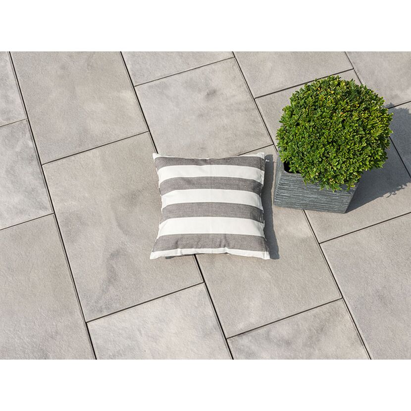 Graue Terrassenplatten mit Kissen und Pflanze