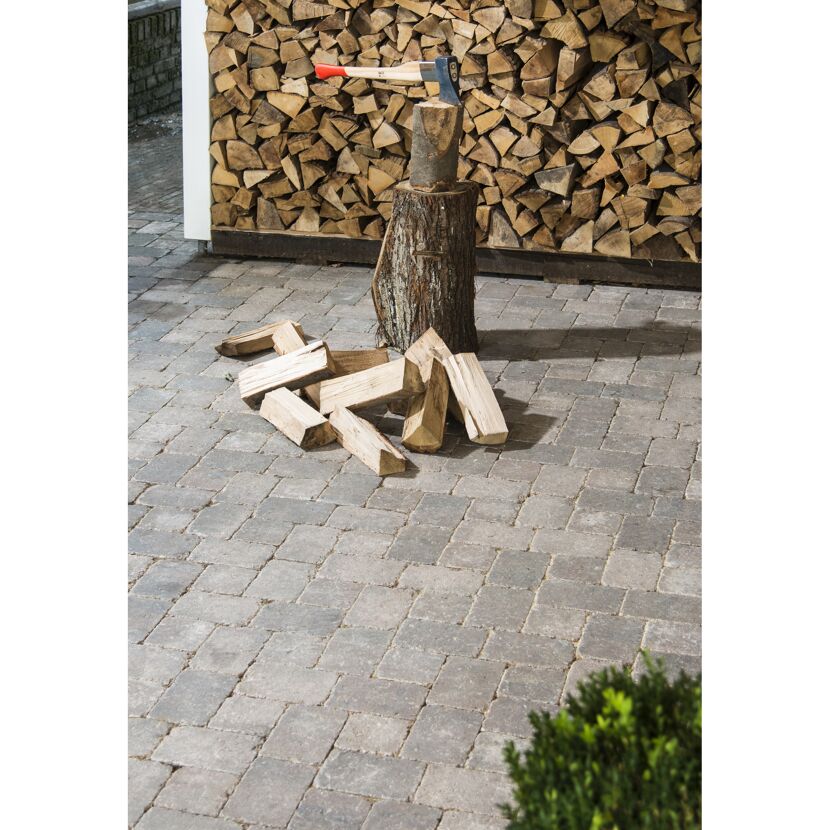 Axt steckt in Holzstamm, daneben liegen Holzscheite.