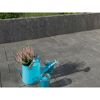Gepflasterte Terrasse mit blauer Gießkanne, Kerzen und Heidekraut.