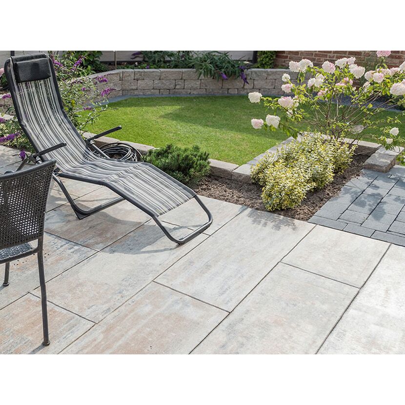 Gepflasterte Terrasse mit Gartenmöbeln und Garten
