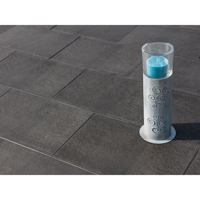 Windlicht mit blauer Kerze auf dunklem Boden.