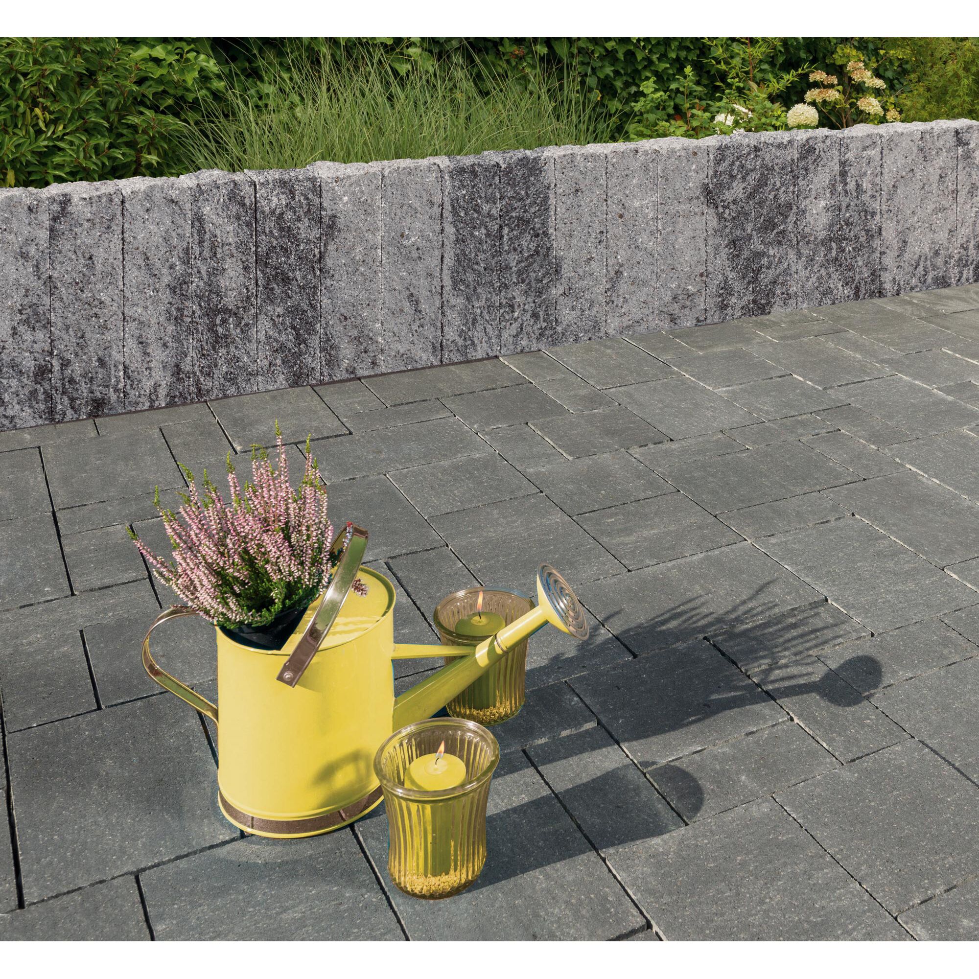 Graue Pflastersteine, gelbe Gießkanne, Kerzenhalter