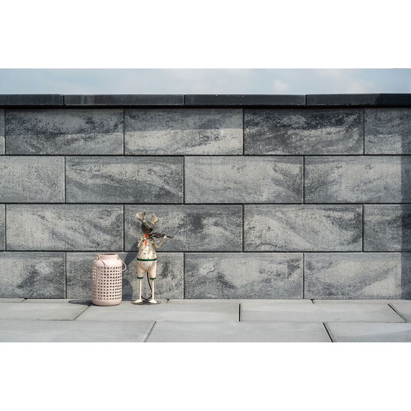 Graue Steinmauer mit Dekofigur und Laterne