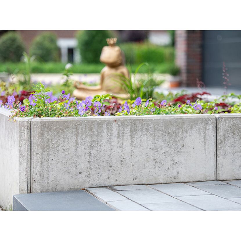 Grauer L-Stein im Garten mit Blumen und Froschfigur