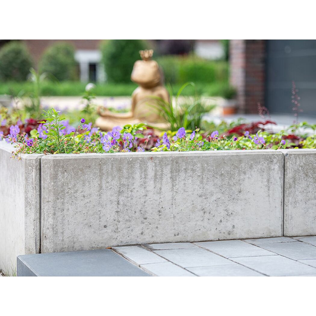 Grauer L-Stein im Garten mit Blumen und Froschfigur