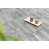 Zwei graue Stumpenkerzen auf einem Holztablett auf grauen Terrassenplatten