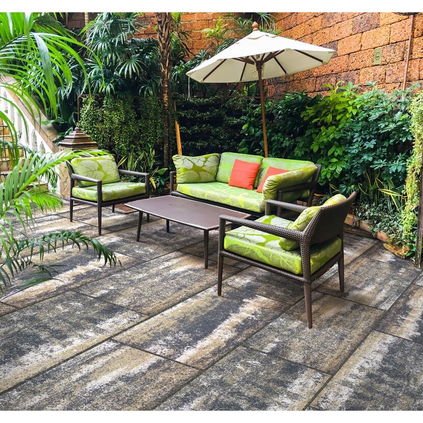 Gepflasterte Terrasse mit Gartenmöbeln und Sonnenschirm.
