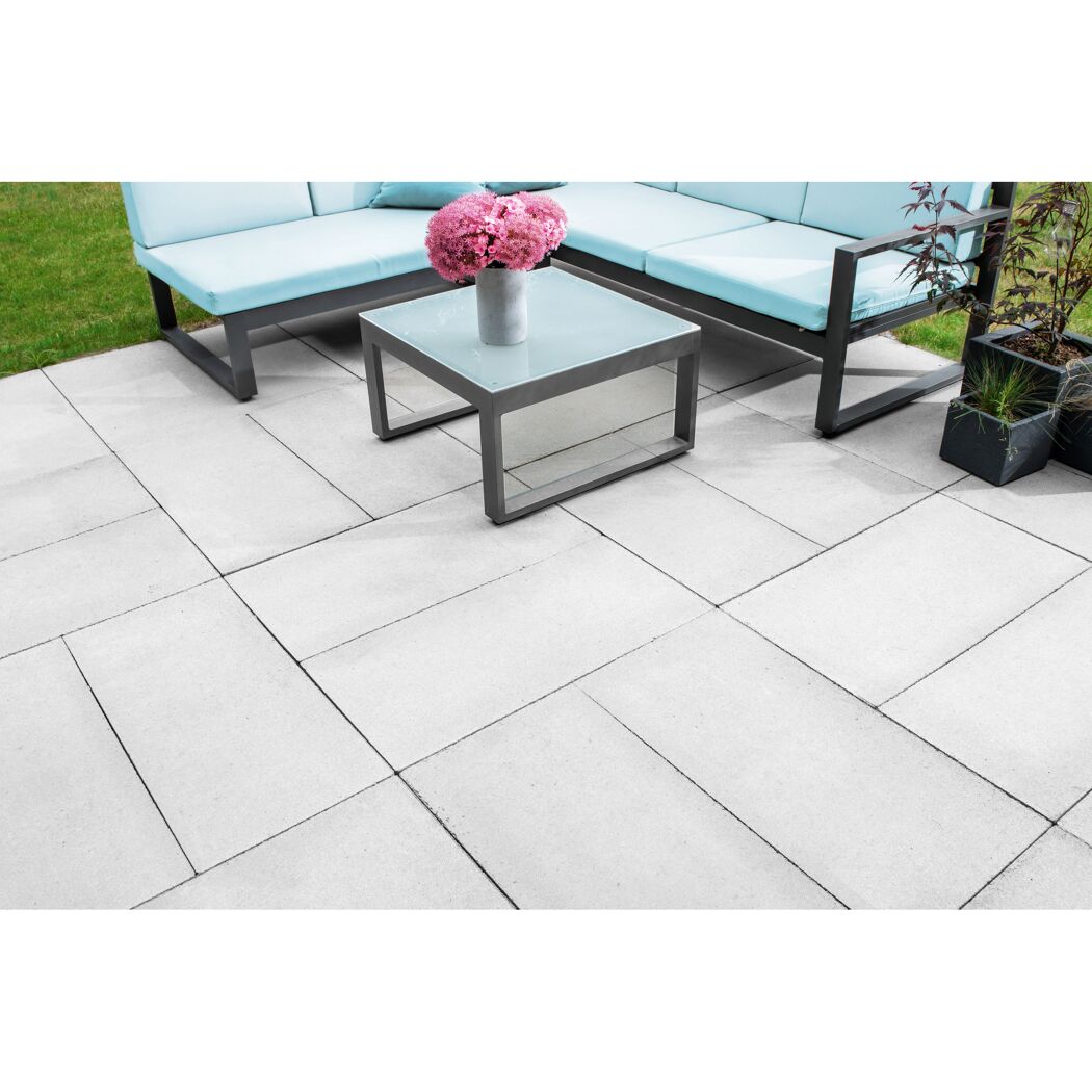 Helle Betonplatten im Garten mit hellblauer Gartencouch und Tisch