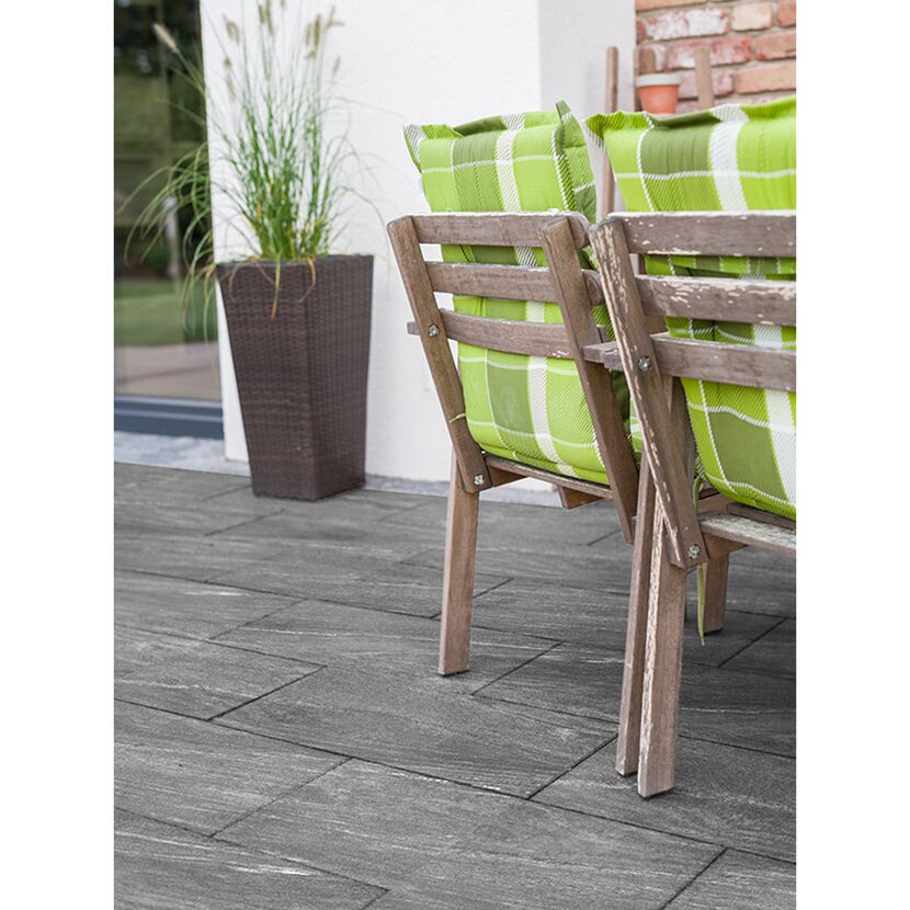 Graue Terrassenplatte mit Gartenmöbel und Pflanze