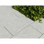 Graue Terrassenplatten neben grünen Pflanzen.