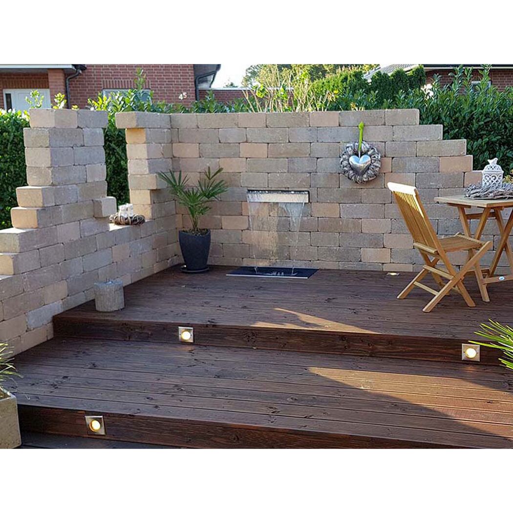 Holzterrasse mit Wasserspiel und Steinwand