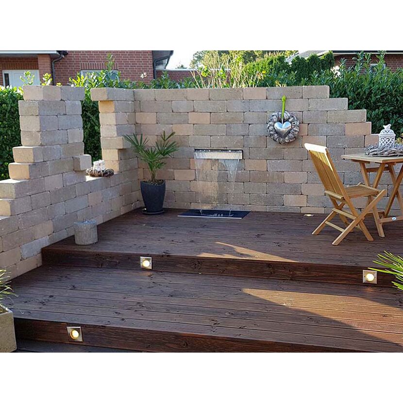 Holzterrasse mit Wasserspiel und Steinwand