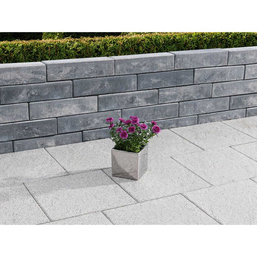 Blumentopf vor grauer Gartenmauer