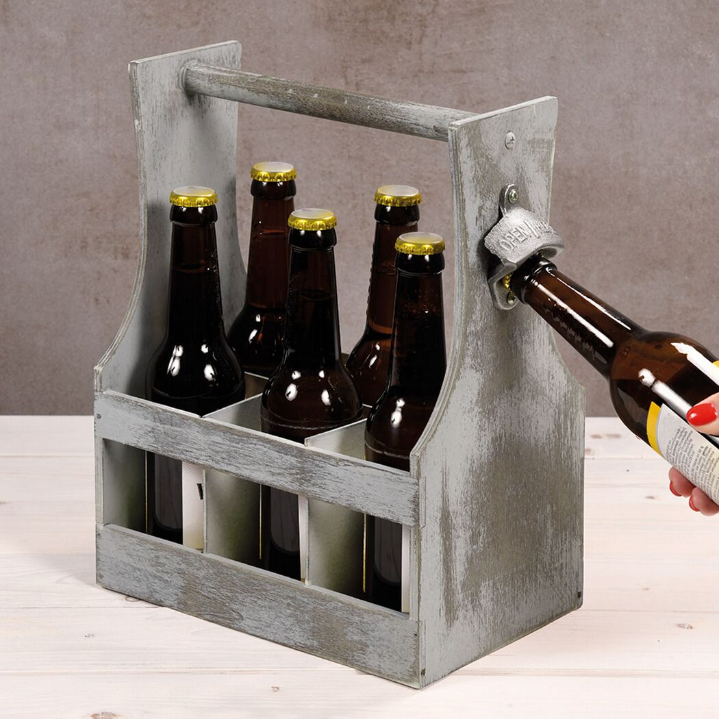 Sechs Flaschen Bier in Holzkiste, eine wird mit Flaschenöffner geöffnet