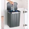Person wirft Plastikflasche in einen Tür-Abfalleimer.
